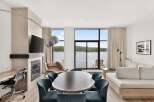 Experience luxury living with this stunning lakefront suite, featuring a modern fireplace and a spacious dining area perfect for entertaining.