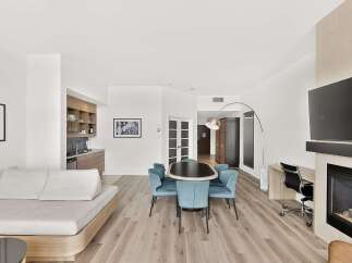 This spacious suite offers a modern living area with a comfortable sofa and a dedicated dining space featuring a sleek table and chairs.