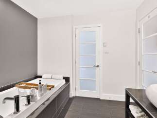 Indulge in relaxation in this luxurious bathroom featuring a deep soaking tub with a wooden tray, perfect for holding bath essentials.