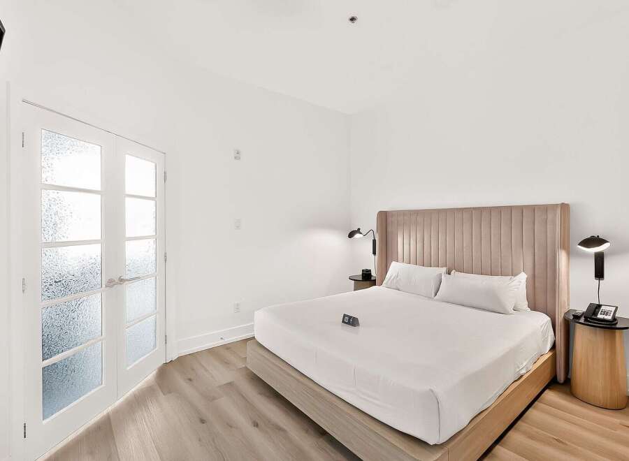Experience modern comfort in this beautifully appointed bedroom, featuring a plush king-sized bed with crisp white linens and a stylish upholstered headboard.