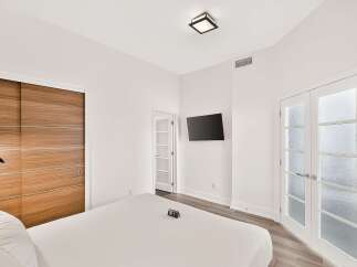 Experience modern luxury in this beautifully appointed bedroom, featuring a sleek wall-mounted TV and a stylish wood-paneled closet.