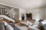 Cozy living room featuring a stone fireplace and a modern staircase.