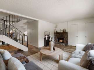 Cozy living room featuring a stone fireplace and a modern staircase.