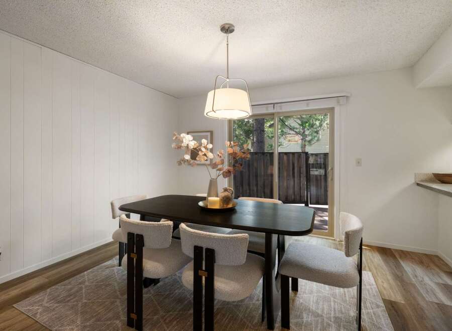 This dining area features a modern dark wood table paired with stylish boucle chairs, creating an inviting space for meals.
