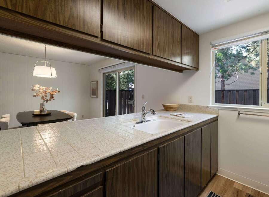 This kitchen features a tiled countertop with a double basin sink and a chrome faucet, complemented by dark wood cabinetry.