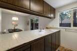 This kitchen features a tiled countertop with a double basin sink and a chrome faucet, complemented by dark wood cabinetry.