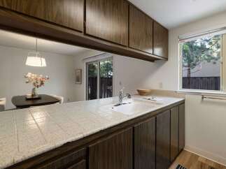 This kitchen features a tiled countertop with a double basin sink and a chrome faucet, complemented by dark wood cabinetry.