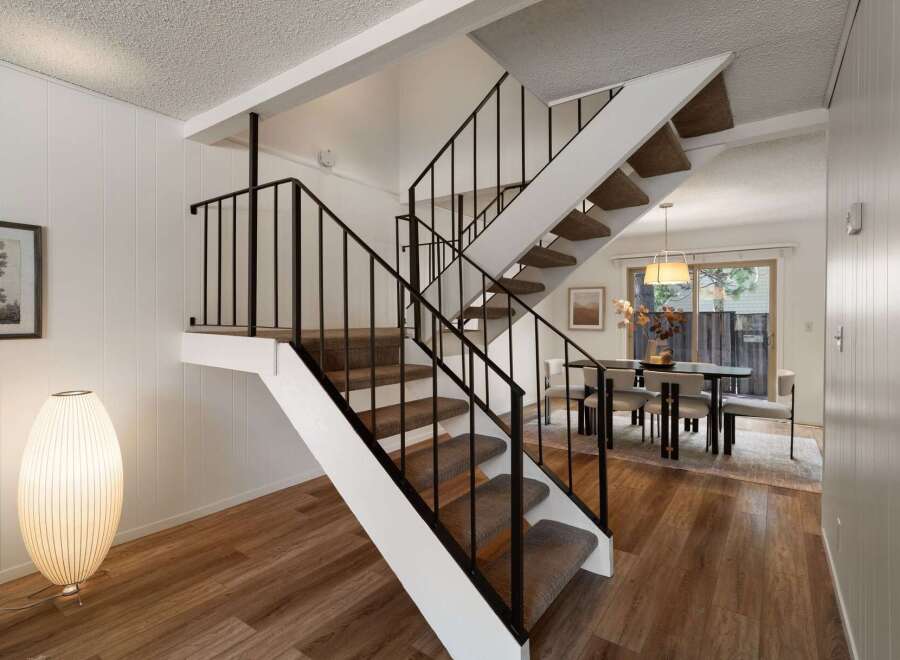 Ascend to the upper level via a striking staircase featuring a modern black railing and plush carpeted steps.