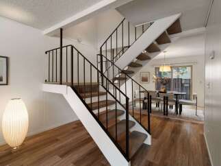 Ascend to the upper level via a striking staircase featuring a modern black railing and plush carpeted steps.