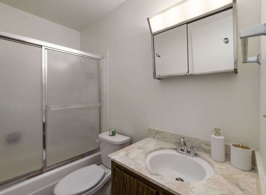 This bathroom features a convenient bathtub with a sliding glass door, perfect for a quick shower or a relaxing bath.