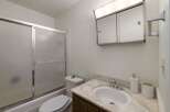 This bathroom features a convenient bathtub with a sliding glass door, perfect for a quick shower or a relaxing bath.