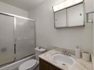 This bathroom features a convenient bathtub with a sliding glass door, perfect for a quick shower or a relaxing bath.