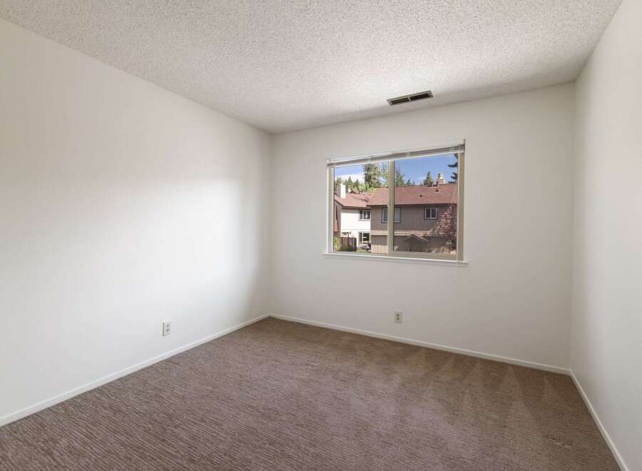 This bright and airy room features neutral carpeting and clean white walls, creating a versatile canvas for any decor style.