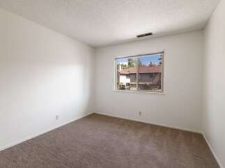 This bright and airy room features neutral carpeting and clean white walls, creating a versatile canvas for any decor style.