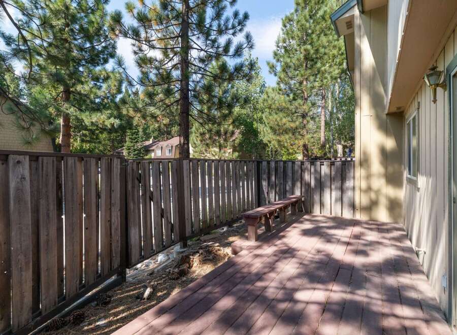 Enjoy outdoor living on this spacious wooden deck, perfect for entertaining or relaxing amidst a serene, tree-lined backyard.