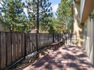 Enjoy outdoor living on this spacious wooden deck, perfect for entertaining or relaxing amidst a serene, tree-lined backyard.