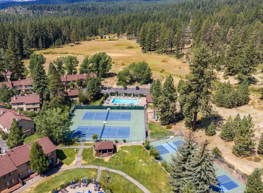 Discover resort-style living with this aerial view showcasing multiple tennis courts and a sparkling swimming pool, perfect for recreation and relaxation.