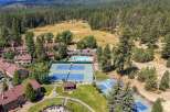 Discover resort-style living with this aerial view showcasing multiple tennis courts and a sparkling swimming pool, perfect for recreation and relaxation.