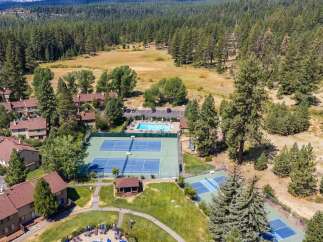 Discover resort-style living with this aerial view showcasing multiple tennis courts and a sparkling swimming pool, perfect for recreation and relaxation.