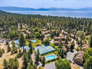 Discover this stunning property nestled amidst a lush pine forest, offering breathtaking views of a serene lake and distant mountains.