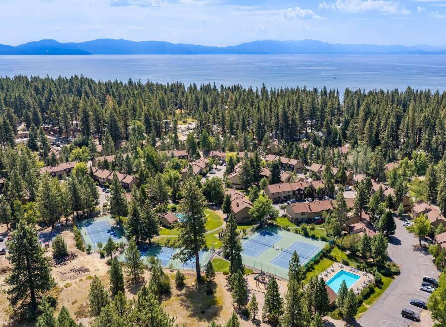 Discover this stunning aerial view of a resort-style community nestled amongst lush pine trees, offering a serene escape.