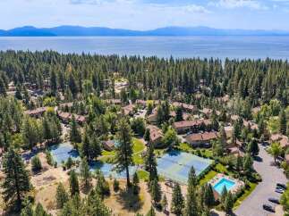 Discover this stunning aerial view of a resort-style community nestled amongst lush pine trees, offering a serene escape.