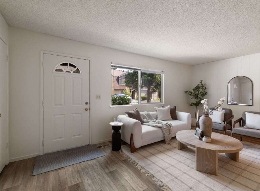 Step into this inviting living space featuring a comfortable white sofa adorned with throw pillows and a cozy blanket, perfect for relaxation.