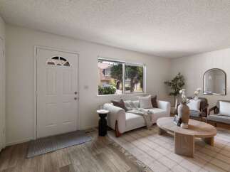 Step into this inviting living space featuring a comfortable white sofa adorned with throw pillows and a cozy blanket, perfect for relaxation.