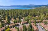 Experience serene living with this stunning aerial view of a lakeside community nestled amongst towering pine trees.