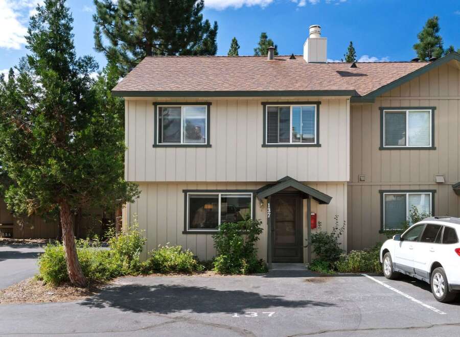 Discover this charming townhouse featuring a light-colored exterior with dark green trim and a classic brown roof.