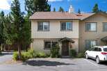 Discover this charming townhouse featuring a light-colored exterior with dark green trim and a classic brown roof.