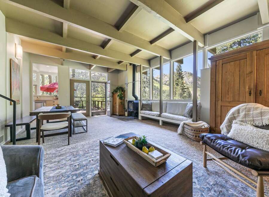 Experience breathtaking mountain views from this stunning living room, featuring a vaulted ceiling with exposed beams and a cozy wood-burning stove.
