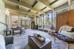 Experience breathtaking mountain views from this stunning living room, featuring a vaulted ceiling with exposed beams and a cozy wood-burning stove.