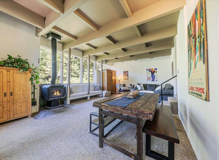 Experience cozy living in this spacious room featuring a modern wood-burning stove and large windows that offer abundant natural light and scenic views.