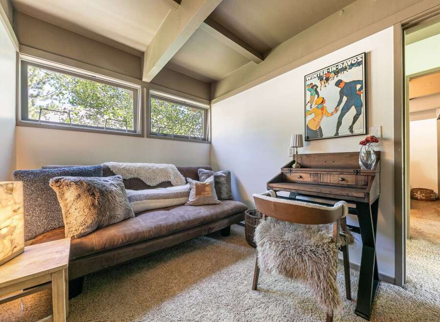 Cozy up in this charming room featuring a comfortable brown sofa adorned with plush pillows and throws.