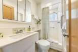 This bright and clean bathroom features a spacious vanity with a modern faucet and a large mirrored medicine cabinet.