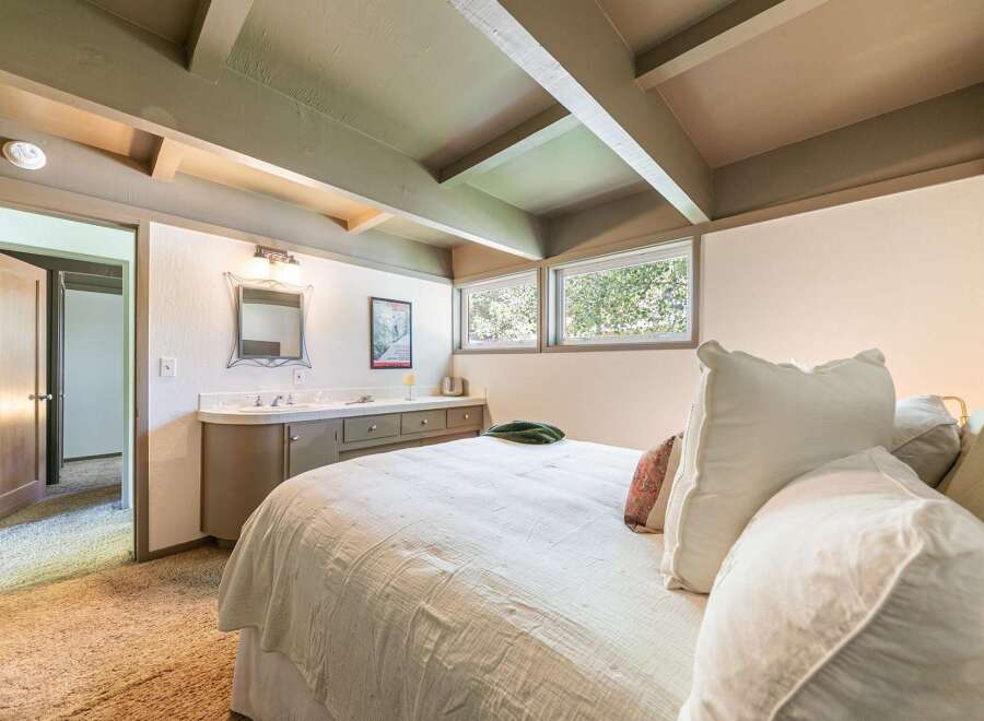 Discover this charming bedroom featuring a cozy bed with plush pillows and a convenient vanity area.