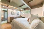 Discover this charming bedroom featuring a cozy bed with plush pillows and a convenient vanity area.