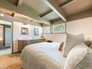 Discover this charming bedroom featuring a cozy bed with plush pillows and a convenient vanity area.