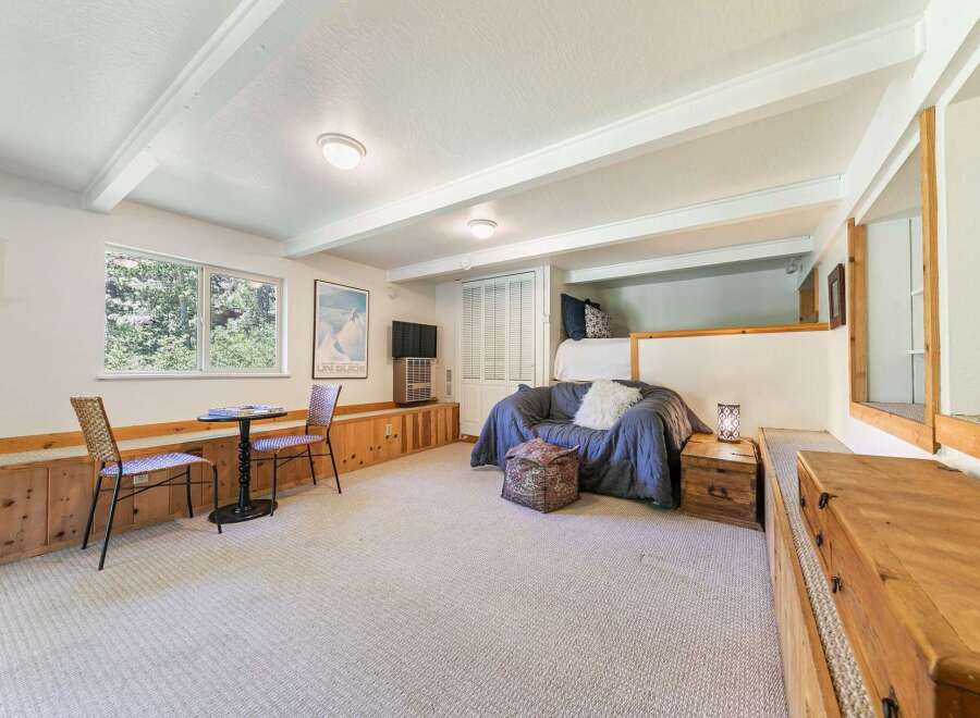 Discover this charming living space featuring a cozy blue sofa and a unique lofted sleeping area.
