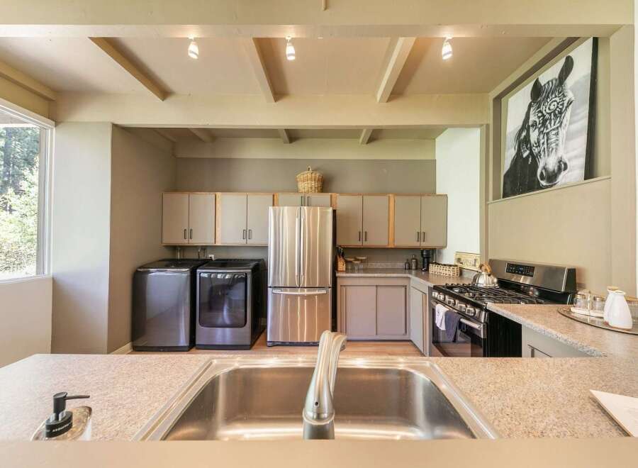 This spacious kitchen features a convenient laundry area with a washer and dryer, complemented by a large stainless steel refrigerator.