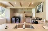 This spacious kitchen features a convenient laundry area with a washer and dryer, complemented by a large stainless steel refrigerator.