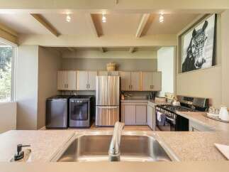 This spacious kitchen features a convenient laundry area with a washer and dryer, complemented by a large stainless steel refrigerator.
