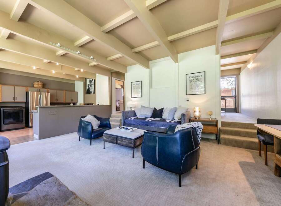 Experience modern living in this spacious open-concept home, featuring a stylish living area with comfortable seating and a striking Picasso-inspired art piece.