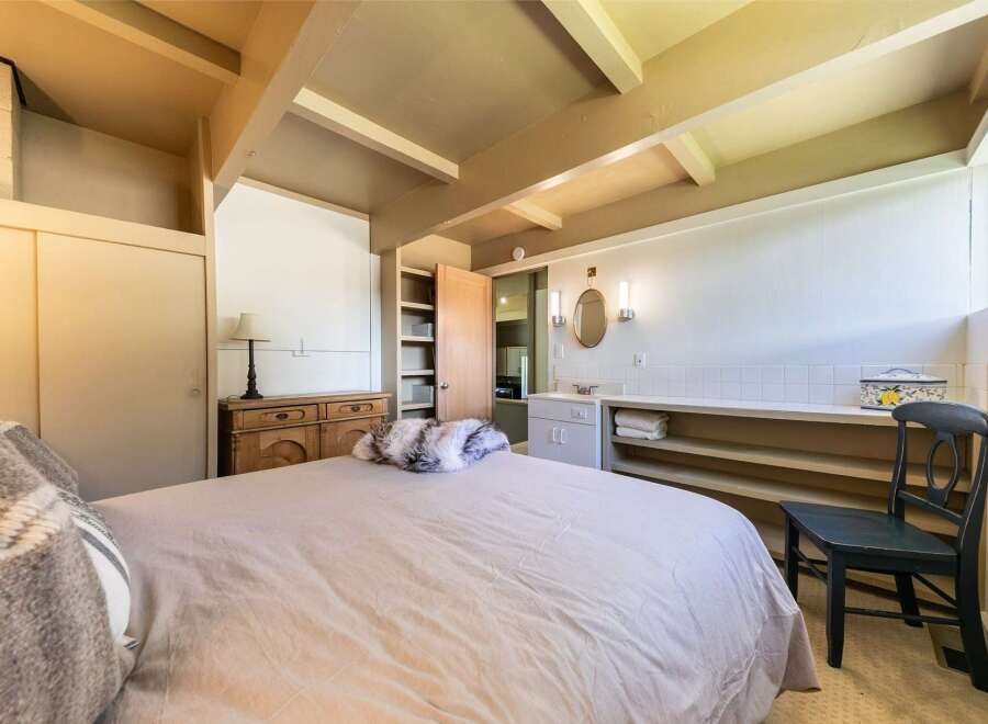 Discover this charming bedroom featuring a cozy bed with plush throws and a rustic wooden dresser.