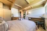 Discover this charming bedroom featuring a cozy bed with plush throws and a rustic wooden dresser.