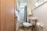 This cozy bathroom features a convenient shower with a striped curtain and a toilet with a plush mat on top.