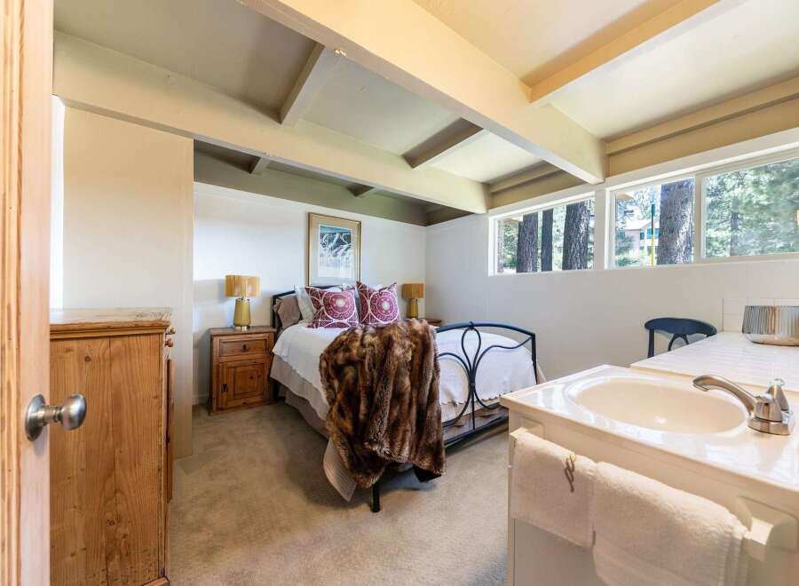 Discover this charming bedroom featuring a cozy queen-size bed adorned with a luxurious faux fur throw and decorative pillows.