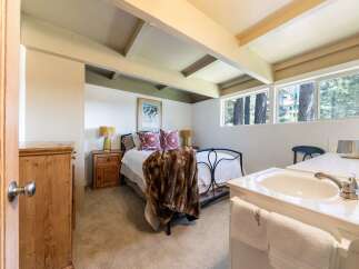 Discover this charming bedroom featuring a cozy queen-size bed adorned with a luxurious faux fur throw and decorative pillows.