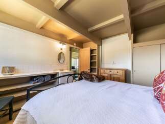 Discover a unique bedroom featuring a charming vanity area with a tiled backsplash and a decorative mirror, complemented by open shelving for storage.